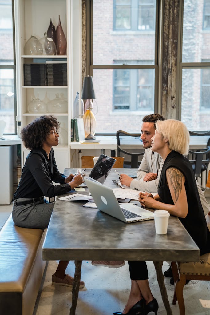 A diverse group of professionals having a meeting at an office table with laptops.