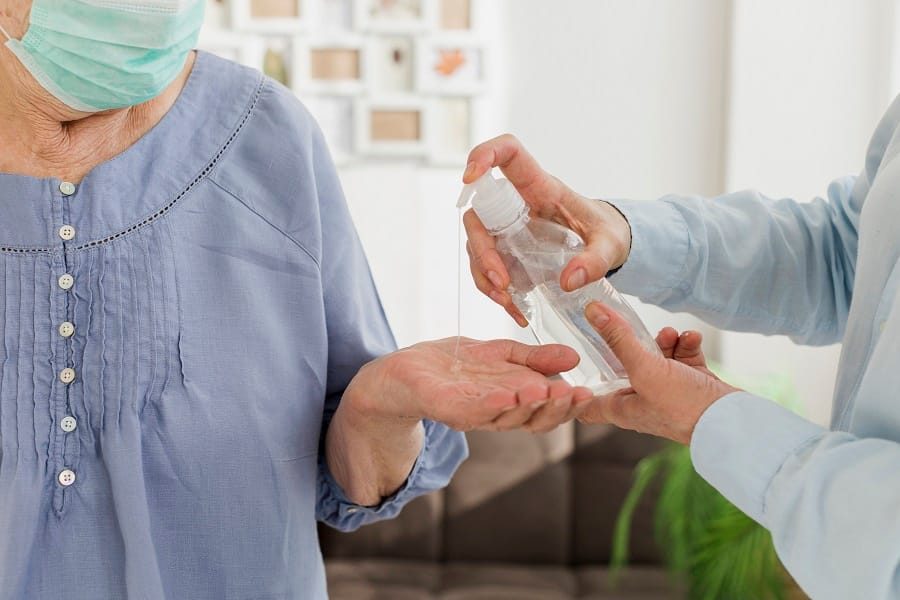 a health professional giving an elderly woman a sanitizer for infection prevention