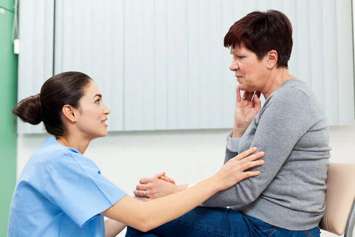 a nurse comforting a patient who appears to be in pain